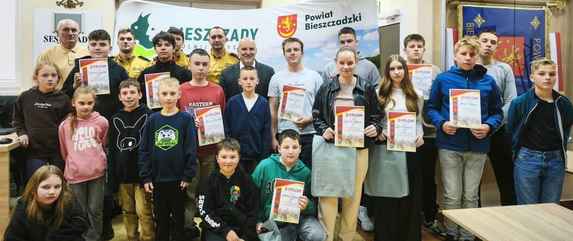 Zdjęcie przedstawia dwóch funkcjonariuszy PSP w Ustrzykach Dolnych, zastępcę komendanta, starostę bieszczadzkiego oraz uczestników turnieju. 