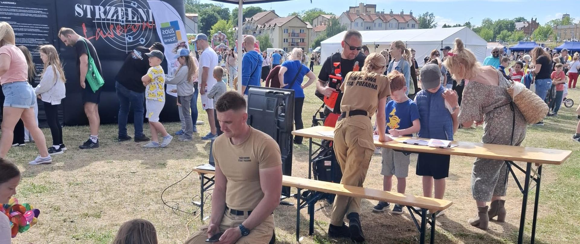 Piknik OLiOC zdjęcie punktu prowadzenia szkoleń z pierwszej pomocy, w tle dużo ludzi na festynie