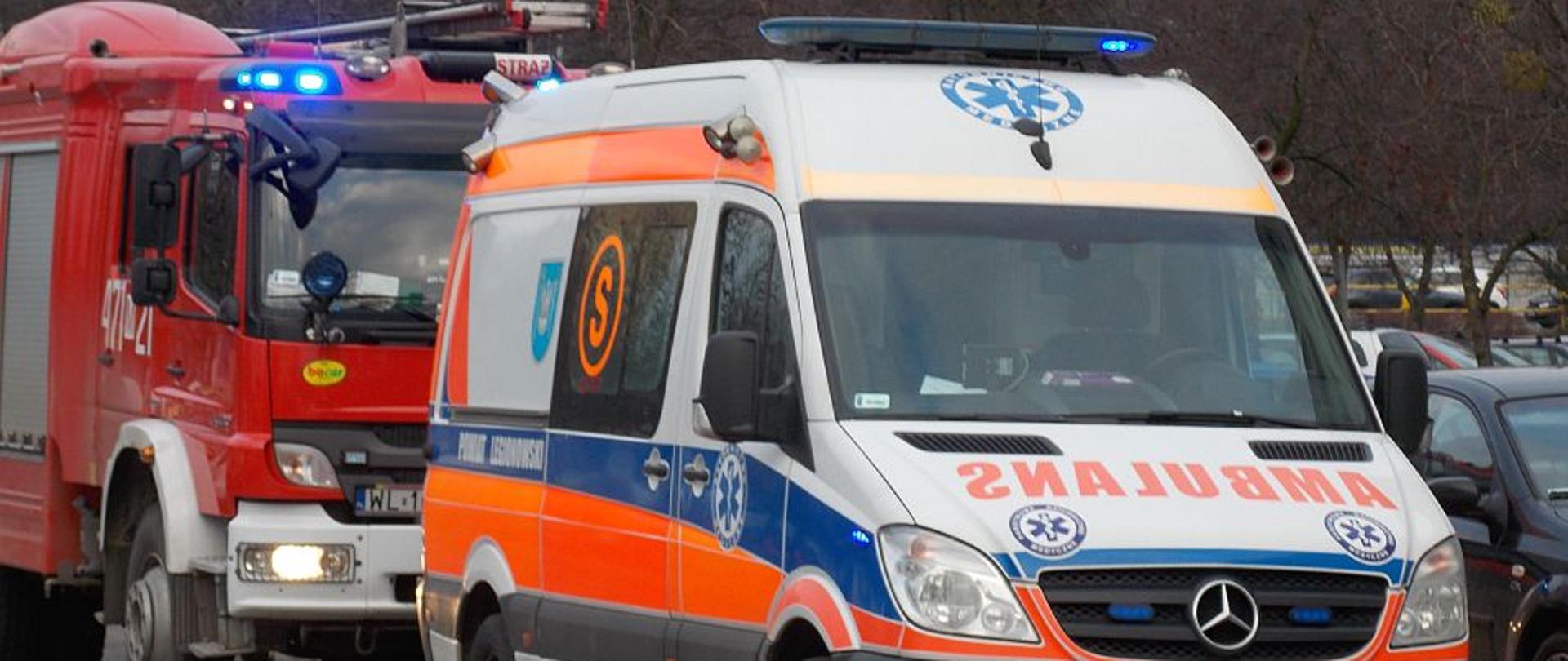 Zdjęcie przedstawia pojazd straży pożarnej oraz karetki na ulicy.