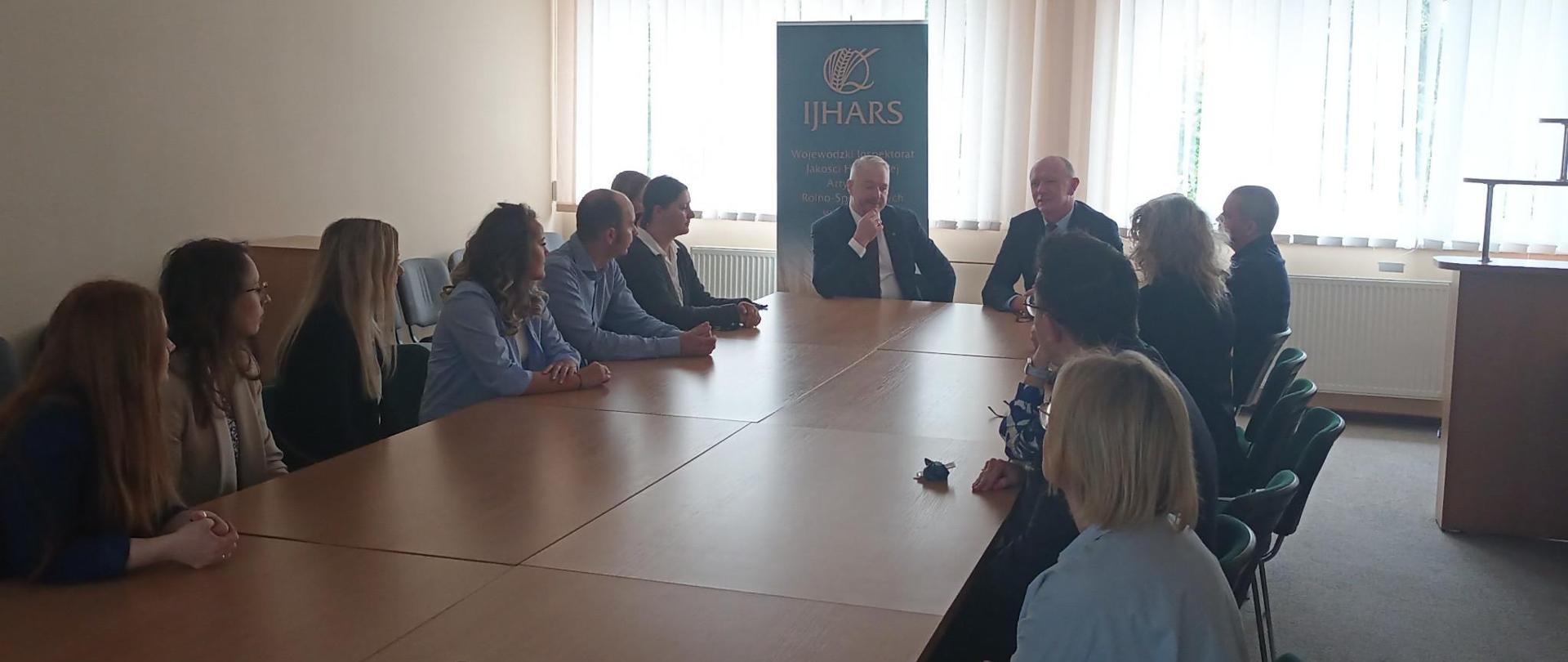 Spotkanie Wojewody Warmińsko-Mazurskiego Pana Radosława Król z Warmińsko-Mazurskim Wojewódzkim Inspektorem JHARS Panem Ryszardem Piórkowskim oraz pracownikami WIJHARS w Olsztynie. Zebrani siedzą przy stole