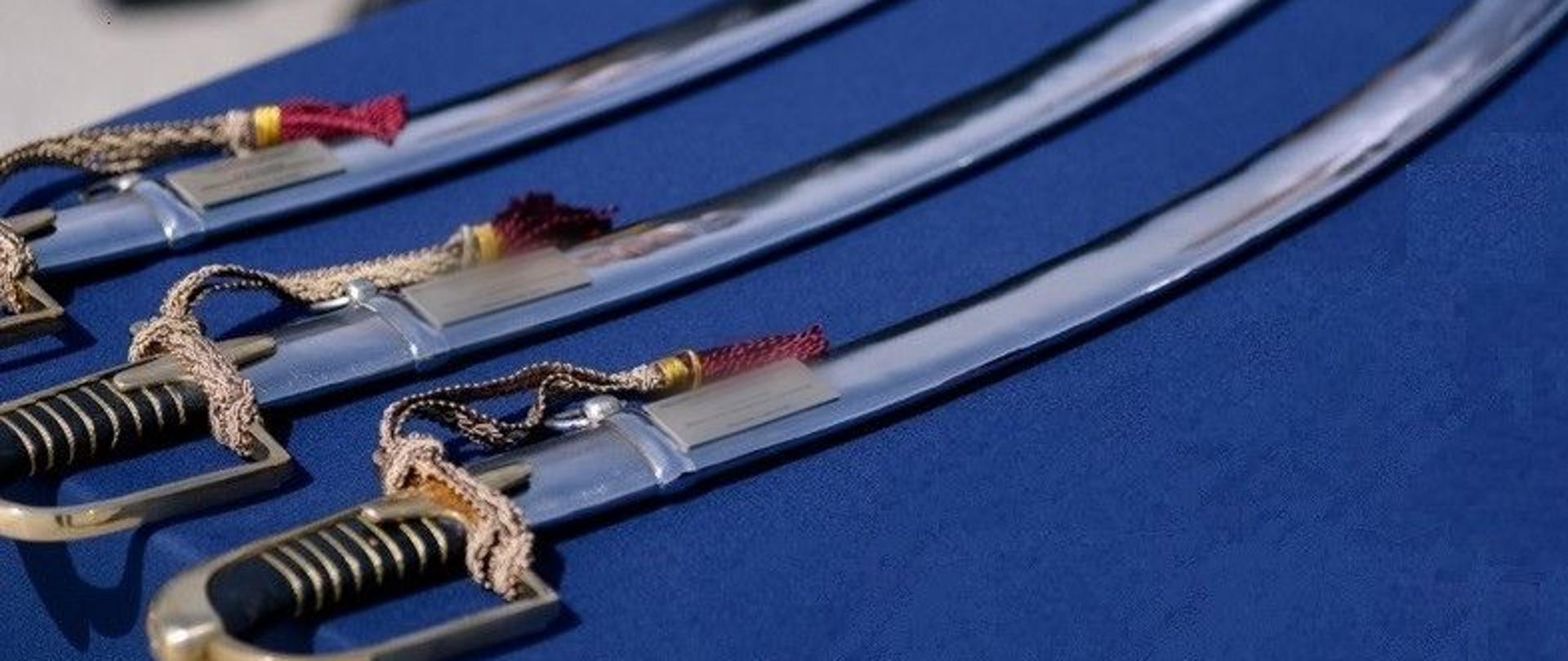 3 szable generalskie ułożone na niebieskim tle