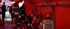W pomarańczowym namiocie ratowniczym znajduję się pięciu strażaków oraz dwóch ratowników medycznych, udzielających pierwszej pomocy, znajdujących się w nim pięciorgu poszkodowanym.