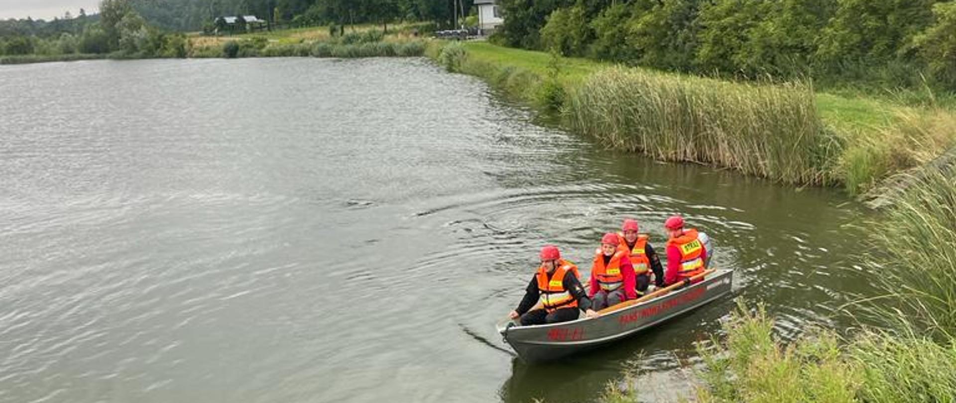 Na zdjęciu widoczni strażacy pływający po akwenie wodnym z łodzi ratowniczej