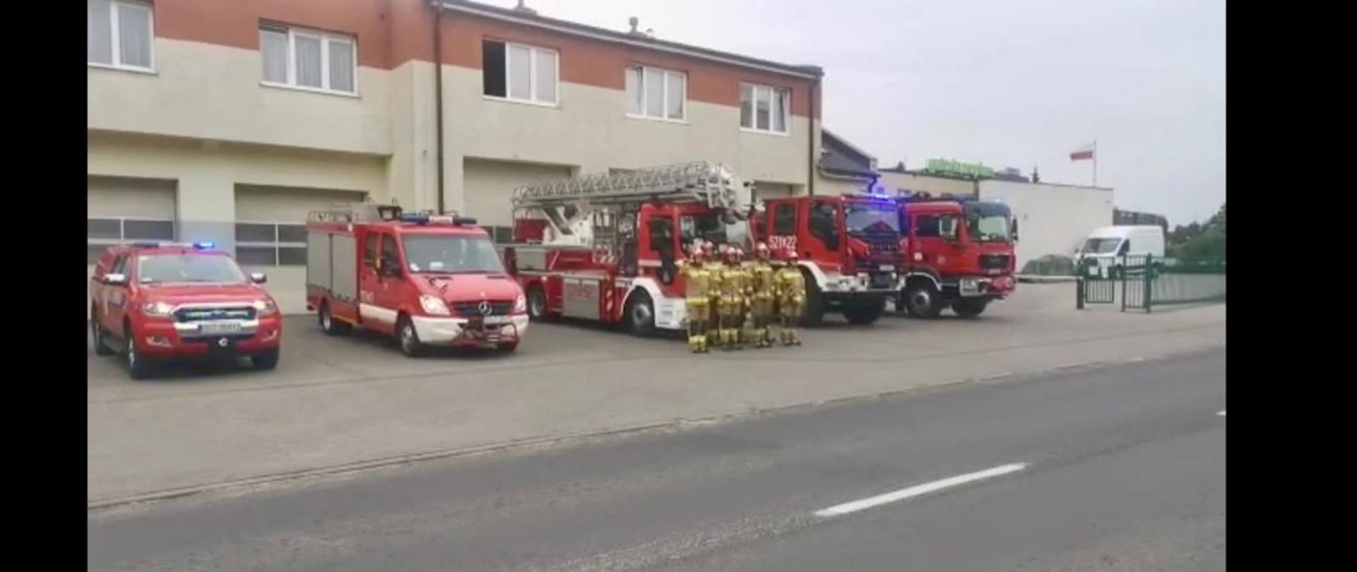 Zdjęcie przedstawia strażaków przed Jednostką, samochody mają włączone sygnały świetlne i dźwiękowe