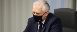 Wicepremier, minister rozwoju, pracy i technologii Jarosław Gowin siedzący za stołem w maseczce na twarzy.