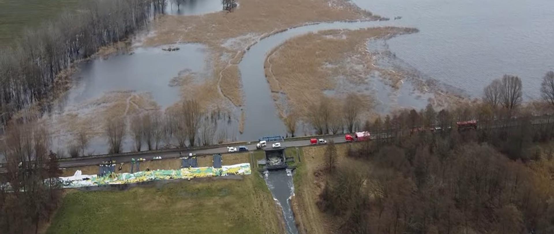 Zakończenie działań przeciwpowodziowych przy Kościańskim Kanale Obry. Strażacy napełniają worki piaskiem, które zostaną ułożone na zaporze czołowej zbiornika Wonieść, wzmacniając wał.