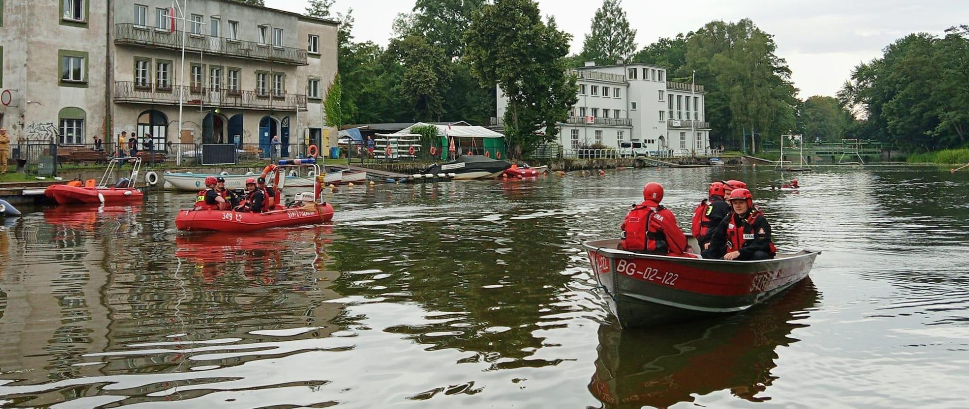 Strażacy płyną w łodzi po rzece.