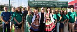 Wspólne zdjęcie uczestników przy stoisku ZSCKR w Okszowie i osobach w strojach ludowych.