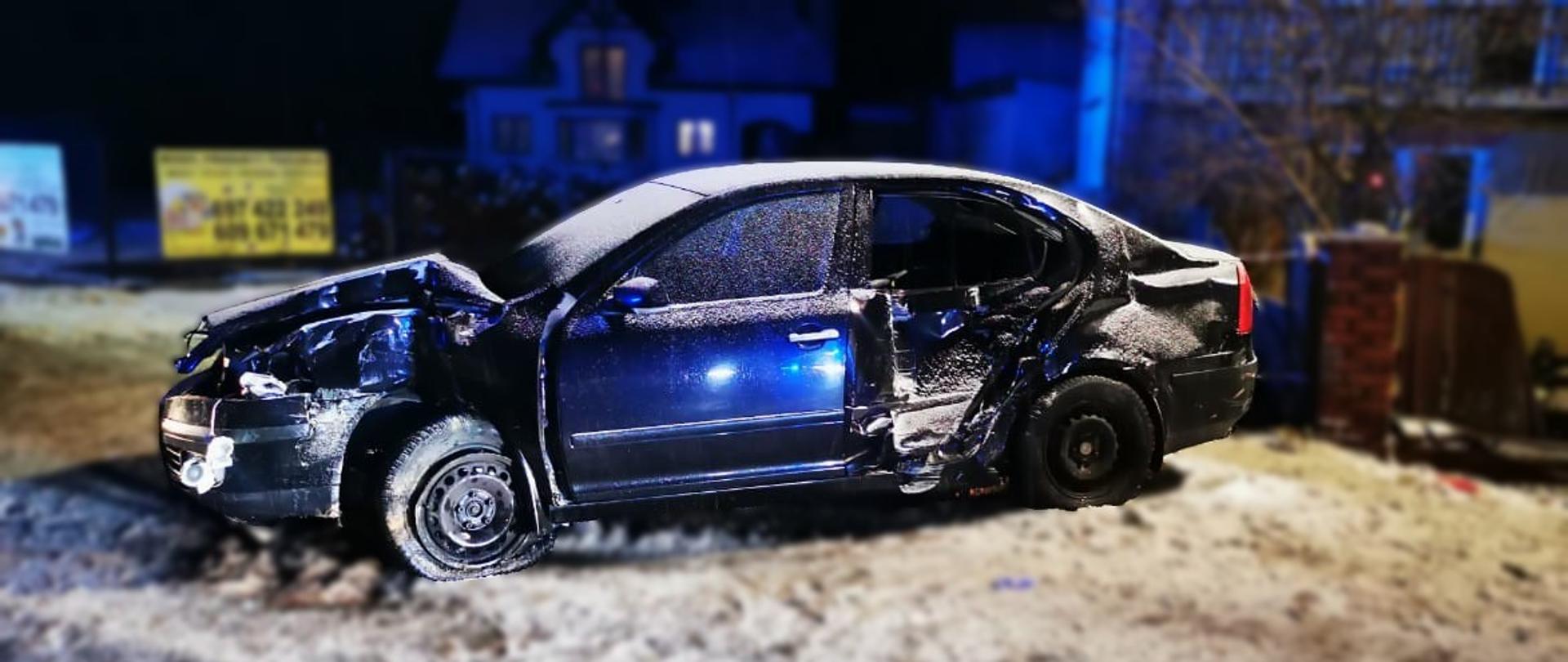 Zdjęcie przedstawia zniszczony w wyniku zderzenia z ogrodzeniem prywatnej posesji samochód osobowy w miejscowości Belno.