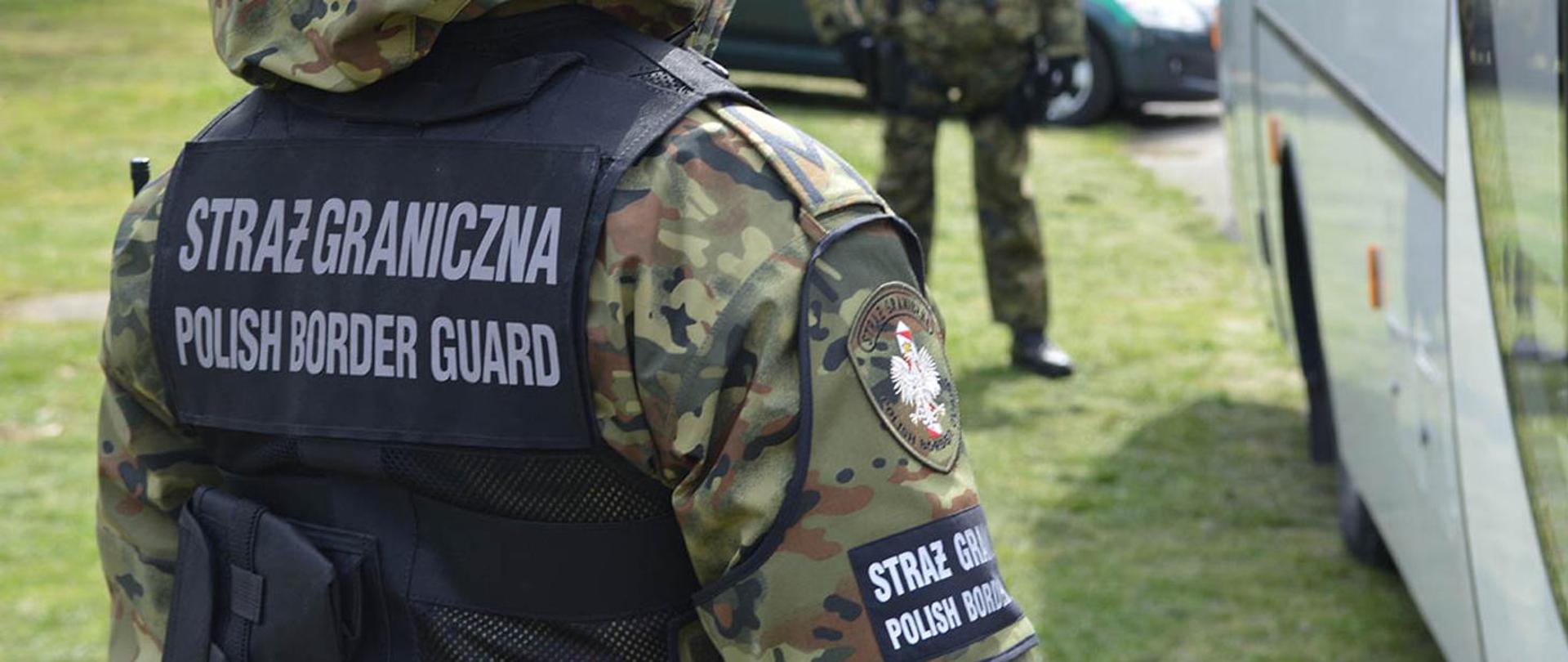 Na zdjęciu strażnik graniczny w mundurze przy autokarze