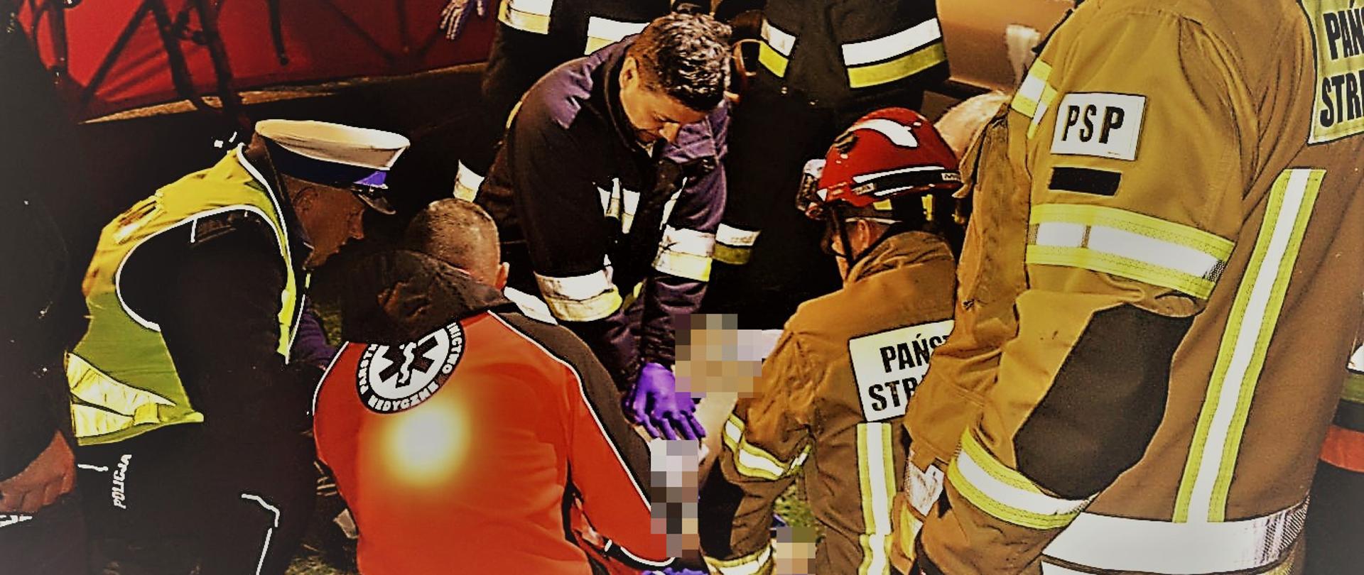 Tragiczne uderzenie w drzewo. Droga Płaczkowo-Bartoszewice. Samochód osobowy peugeot 206 "owinął się" wokół przydrożnego drzewa. Na zdjęciu strażacy, ratownicy medyczni oraz policjanci, którzy prowadzą walkę o życie kierowcy samochodu, u którego wystąpiło nagłe zatrzymanie krążenia. Jeden ze strażaków wykonuje zewnętrzny masaż serca.