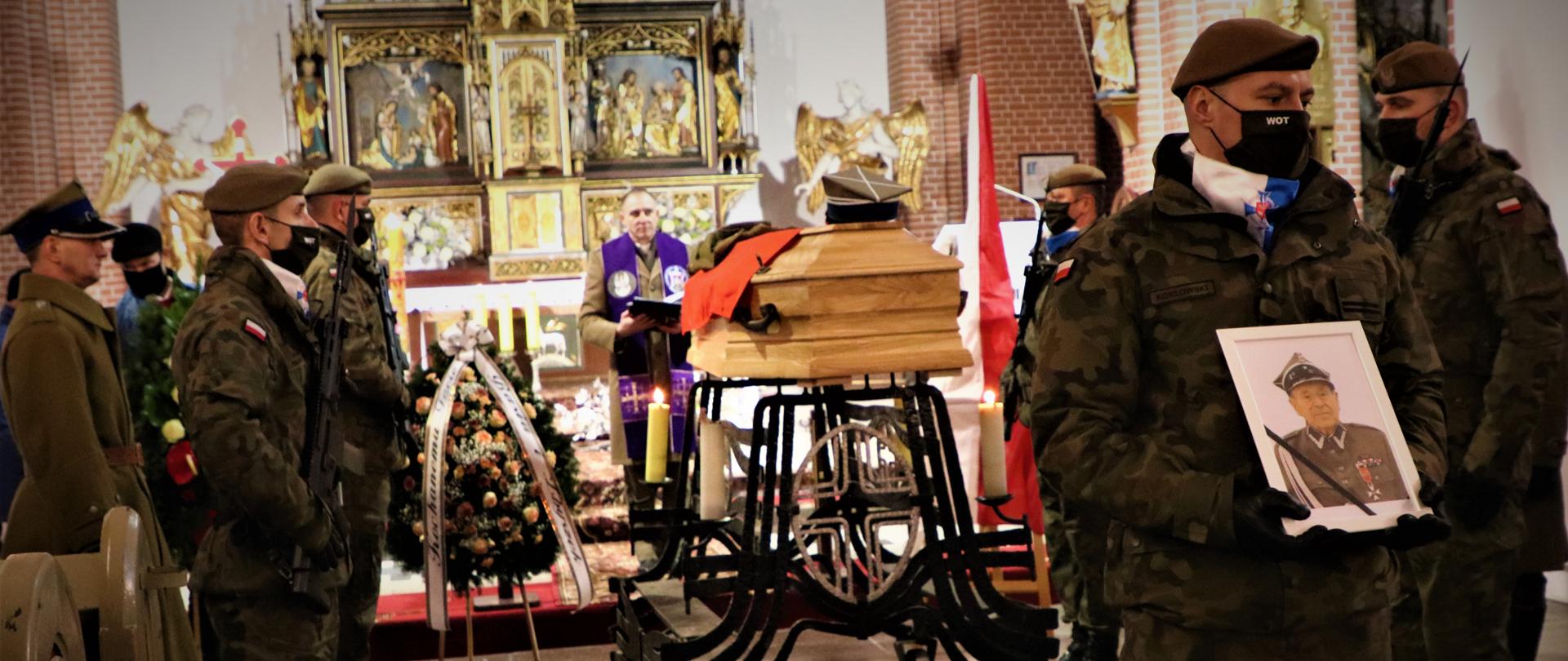 Msza św. żołnierz trzyma portret majora w tle trumna. Żołnierze pełnią wartę honorową