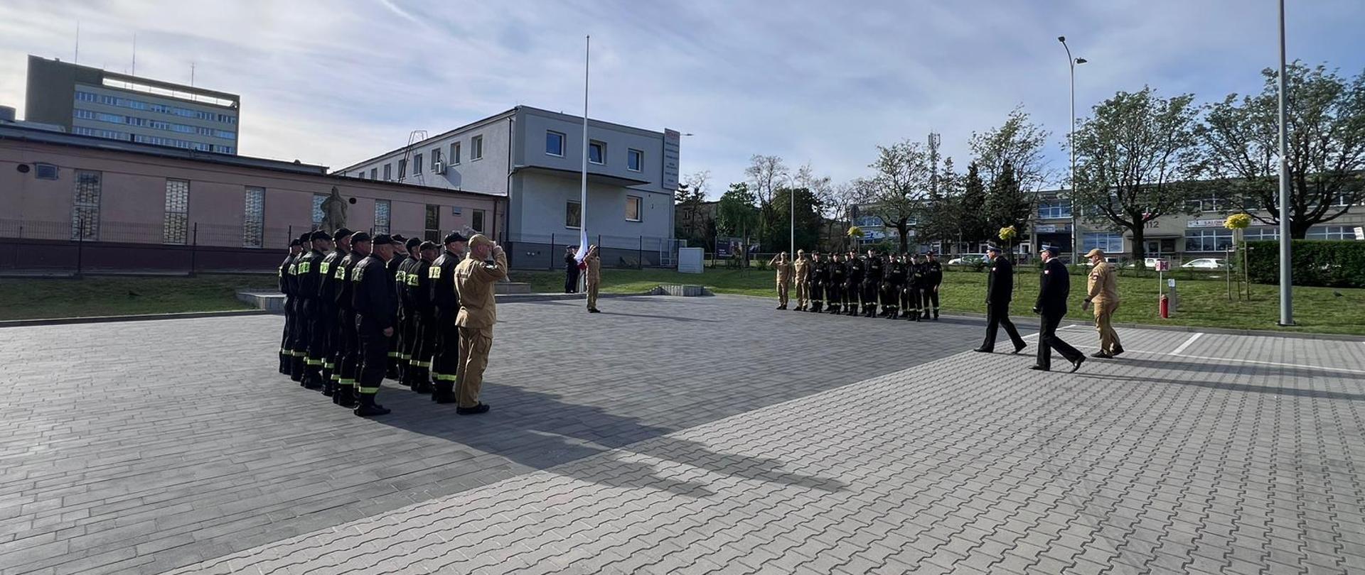 Fotografia przedstawia strażaków w Kielcach podczas uroczystego podnoszenia biało-czerwonej flagi na maszt