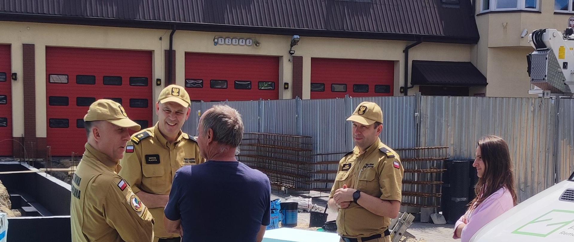 Trzej strażacy w umundurowaniu piaskowym 