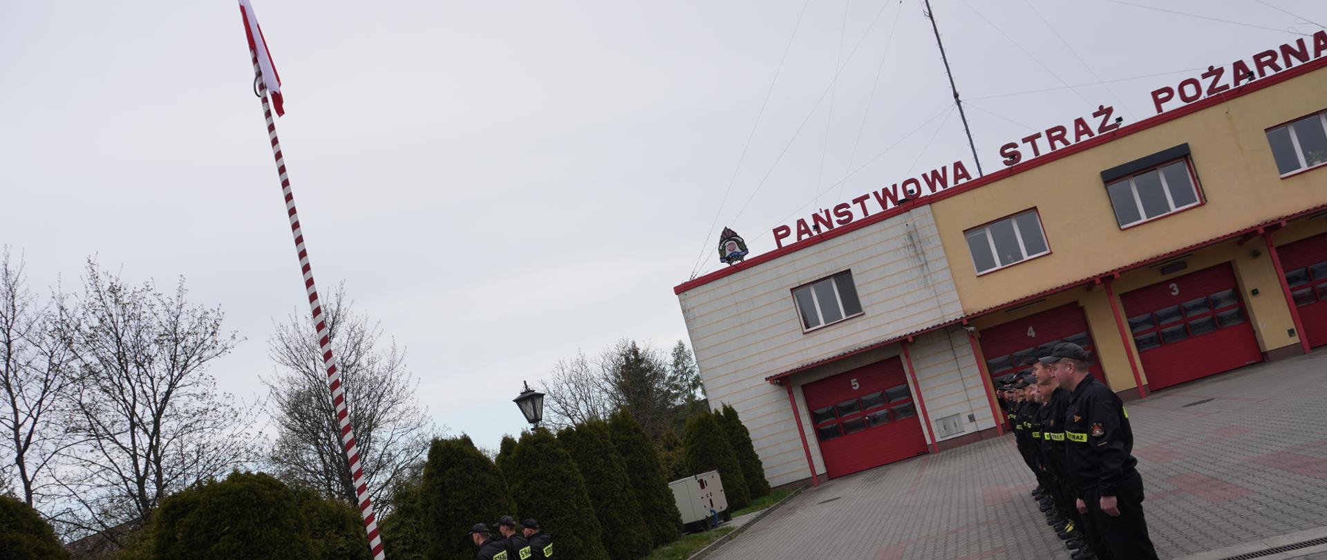 utwardzony plac zewnętrzny komendy, zbiórka w szeregu , poczet flagowy salutuje do flagi