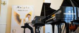 Uczestnik XII Festiwalu Polskiej Muzyki Współczesnej dla Pianistów im. Janiny Garści w Lublińcu przy fortepianie w galowym stroju na sali koncertowej szkoły