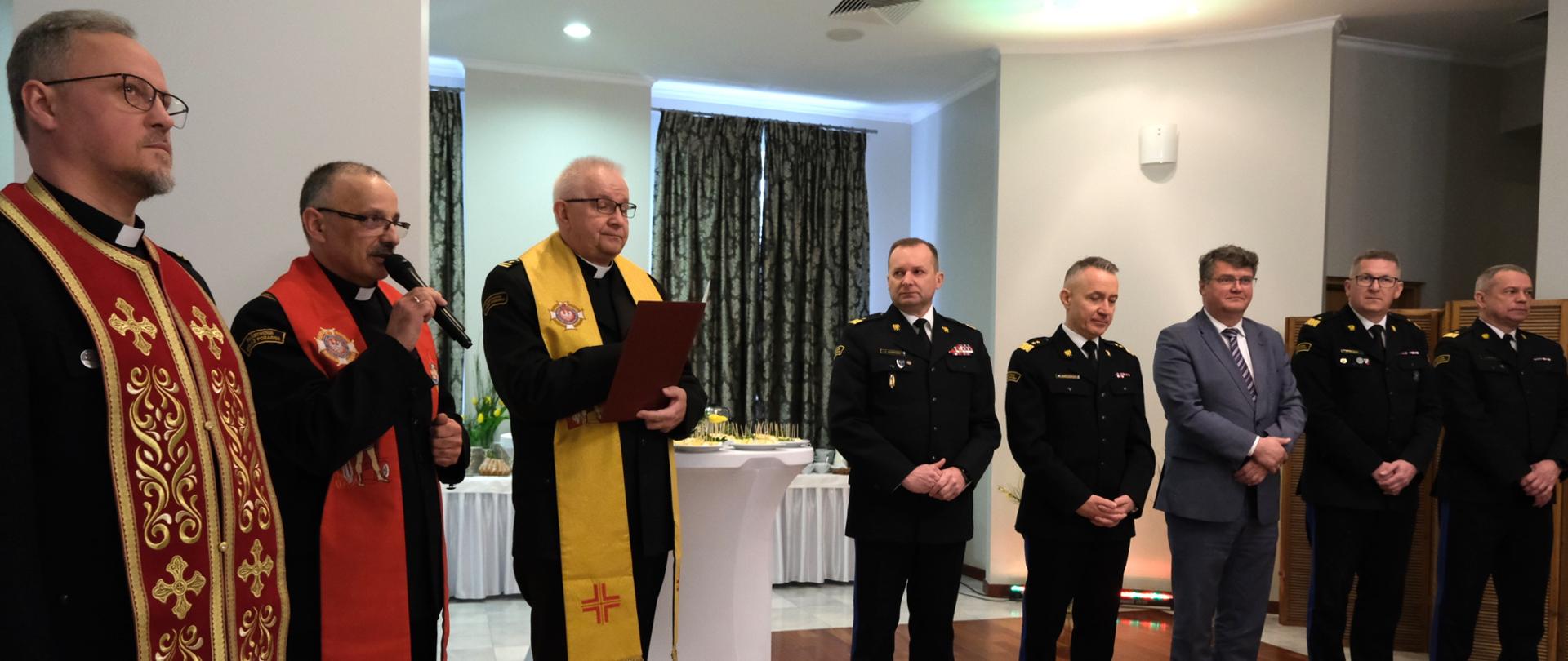 Po lewo trzej kapelani strażaccy, po prawo w szeregu stoją od lewej, zastępca komendanta głównego PSP, komendant główny PSP, wiceminister spraw wewnętrznych i administracji , dwaj zastępcy komendanta głównego PSP