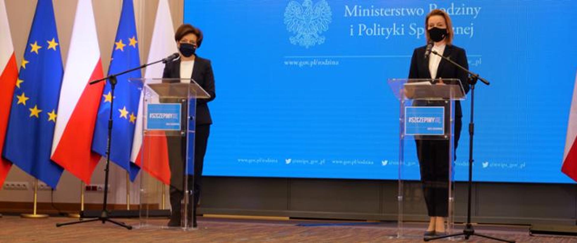 Minister Rodziny i Polityki Społecznej Marlena Maląg oraz Wiceminister Barbara Socha stojące przy mównicach podczas konferencji poświęconej programowi Maluch Plus. W tle niebieska ścianka Ministerstwa Rodziny i Polityki Społecznej. Z lewej strony flagi Polski i Unii Europejskiej. 