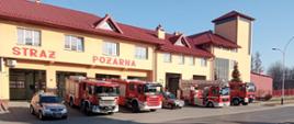 Zdjęcie przedstawia zbiórkę pojazdów z komendy w Przeworsku. Samochody stoją na tle budynku Komendy Powiatowej. Samochody mają włączoną sygnalizację świetlną 