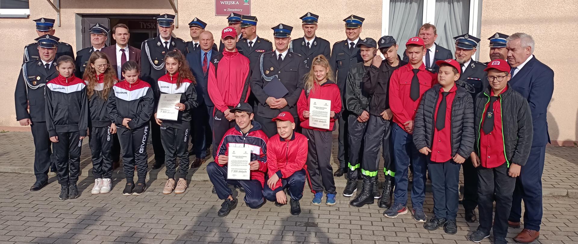 Młodzieżowe Drużyny Pożarnicze z terenu powiatu zambrowskiego wraz z opiekunami trzymają otrzymane promesy 