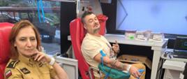 Funkcjonariusze Komendy PSP siedzący na fotelach podczas oddawania krwi. 