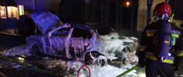 Na zdjęciu widać strażaka z aparatem ochrony dróg oddechowych, który podawał pianę gaśniczą w celu dogaszenia pojazdu. Wrak samochodu oblepiony jest pianą