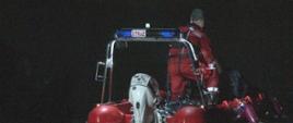Pora nocna. na zdjęciu strażak w ubraniu do pracy w wodzie operuje łódką.