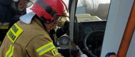 Warsztaty z zakresu ratownictwa technicznego. Złomowisko w Chojnie. Strażacy przy pomocy rozpieracza kolumnowego wykonują dostęp do osoby poszkodowanej znajdującej się w kabinie ciężarówki. 