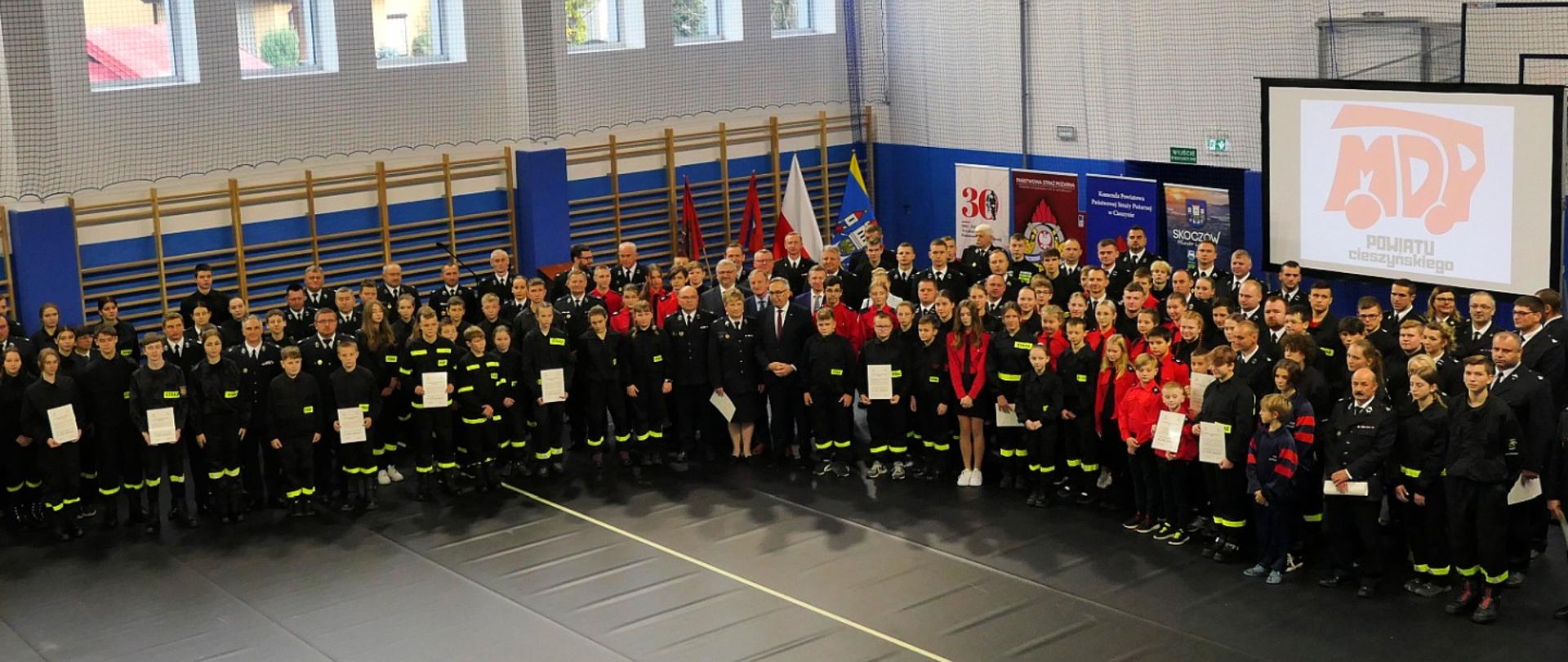 Uroczystość wręczenia promes dotacji celowej dla Ochotniczych Straży Pożarnych na zakup sprzętu dla członków Młodzieżowych Drużyn Pożarniczych z terenu powiatu cieszyńskiego. Środki zostały przyznane przez Ministra Spraw Wewnętrznych i Administracji w ramach dotacji na zadanie publiczne pod nazwą „Przygotowanie jednostek Ochotniczych Straży Pożarnych do działań ratowniczo – gaśniczych”.