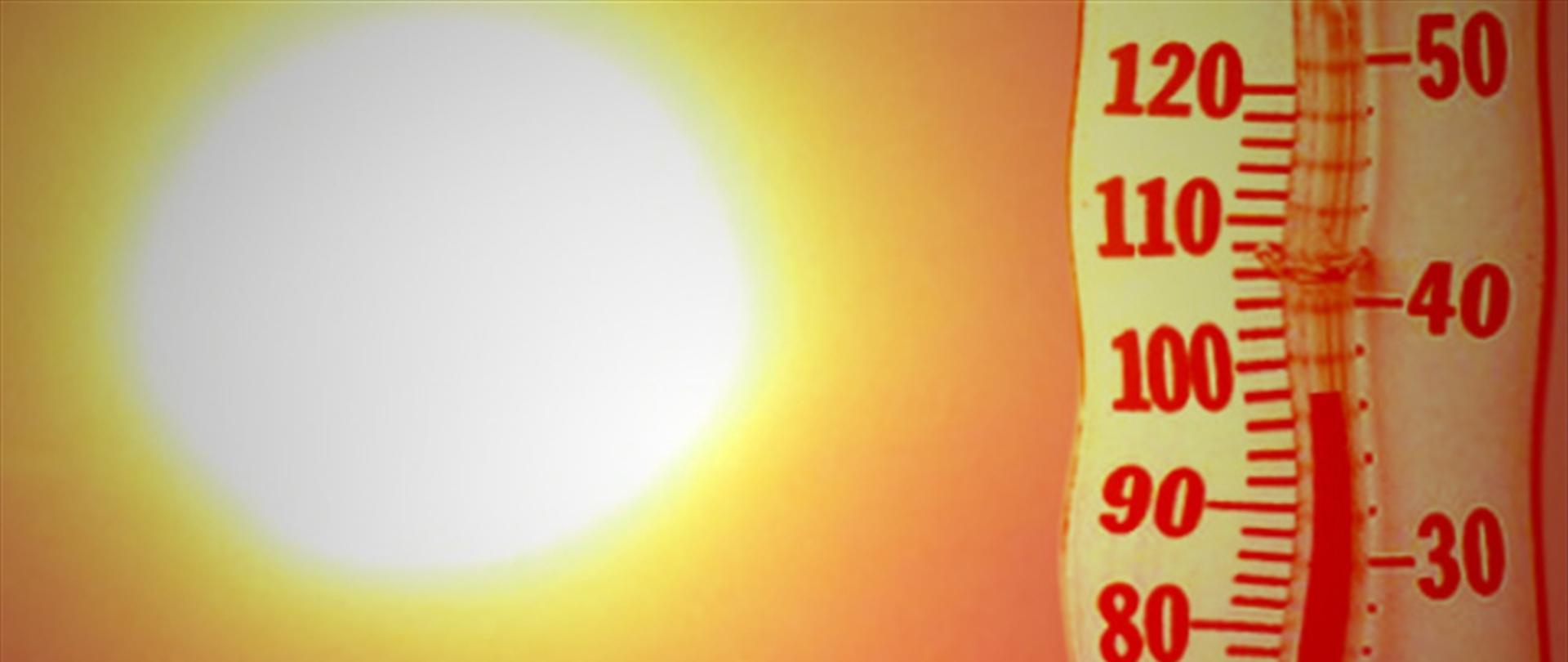 Zbliżenie na termometr wskazujący wysoką temperaturę oraz rozmyte, jasne słońce w tle, symbolizujące upał i falę gorąca.