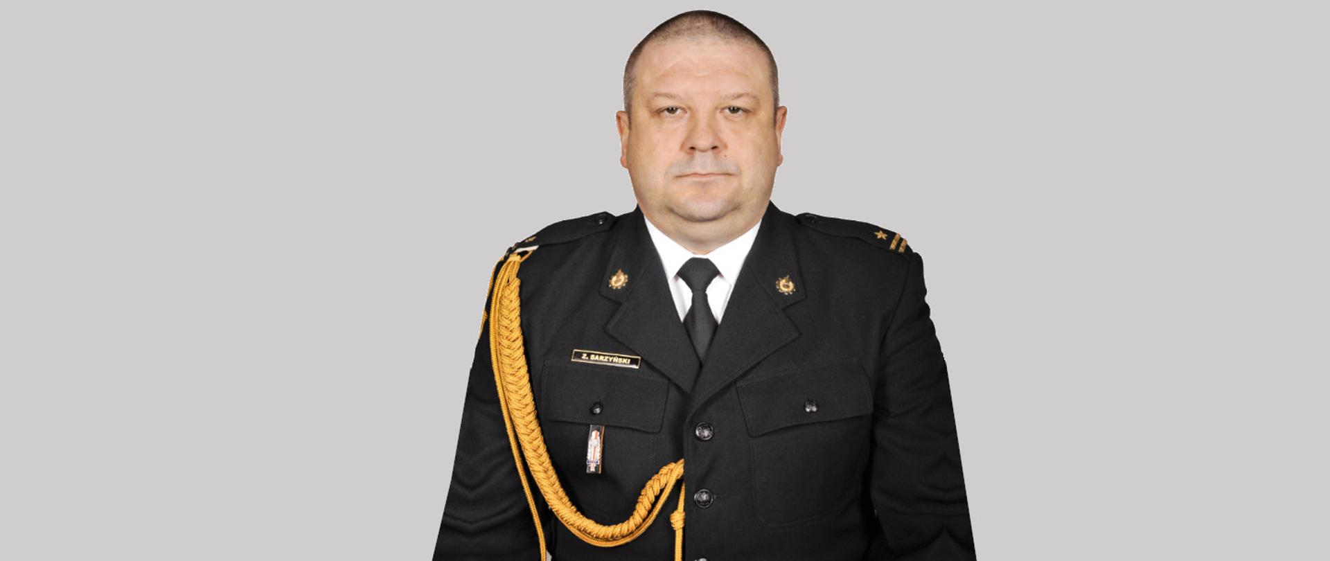 Na zdjęciu widzimy młodszego brygadiera Zbigniewa Sarzyńskiego w umundurowaniu galowym bez nakrycia głowy na szarym tle.