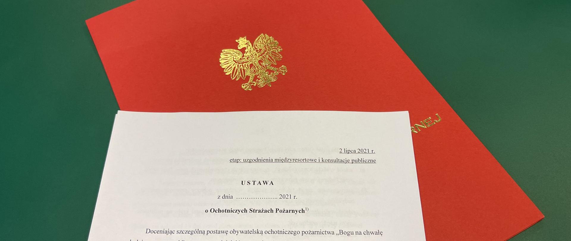 Strona tytułowa projektu ustawy położona na czerwonej teczce ze znakiem orła, ułożone na zielonym tle