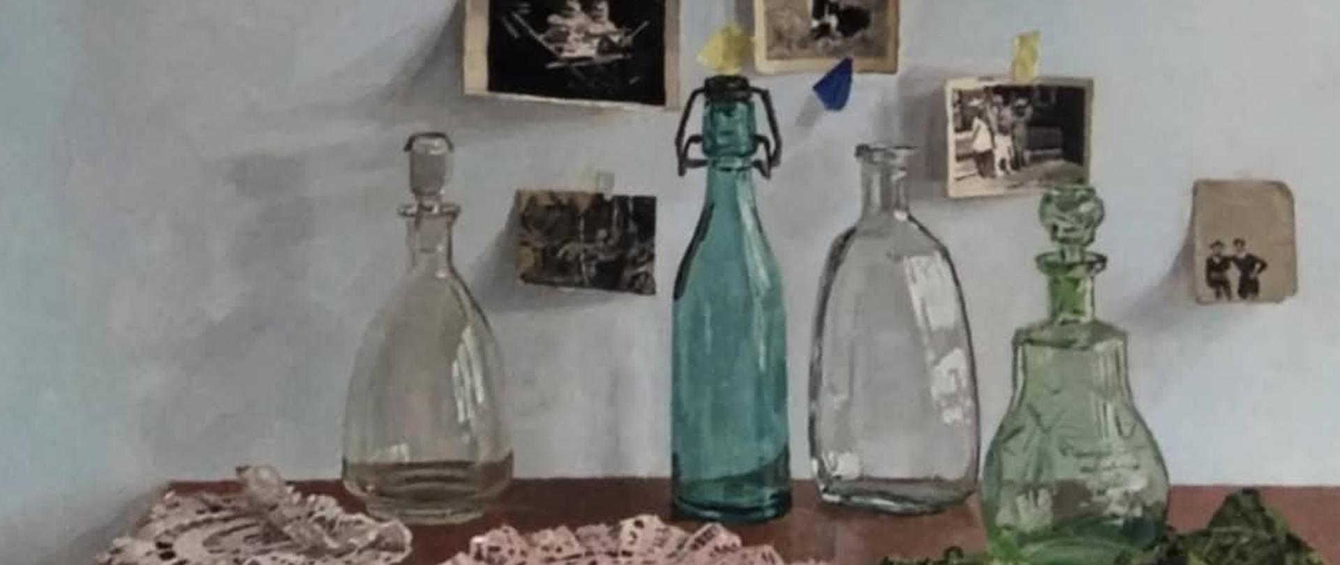 Na zdjęciu widzimy obraz olejny namalowany przez Zuzannę Rumian uczennicę kl. 4B. Praca zdobyła nagrodę Grand Prix na XIV Międzynarodowym Konkursie Plastycznym "Portret Rodzinny" Lublin 2025. Na pierwszym planie widzimy drewniany blat stolika, na którym położone są cztery koronkowe serwetki. Trzy serwetki są z włóczki białej, a jedna z zielonej. Na krawędzi blatu widzimy jeszcze trzy naklejone kawałki taśmy malarskiej. Stolik ustawiony jest pod białą ścianą. Dodatkowo na blacie stolika, tuż pod ścianą ustawione szklane naczynia, od lewej strony szklana przezroczysta karafka ze szklanym korkiem, szklana butelka (w odcieniu błękitu) z zamykanym kapslem z drutu i korka, szklana karafka bez korka i szklana (w zielonym odcieniu) karafka ze szklanym korkiem. Na białej ścianie widzimy osiem czarno-białych, rodzinnych fotografii. Wszystkie fotografie są przyklejone do ściany za pomocą kawałków taśmy malarskiej. Obraz namalowany jest bardzo realistycznie, wręcz w sposób fotograficzny. Mamy wrażenie, że kawałki taśmy malarskiej są naklejone, a nie namalowane. 