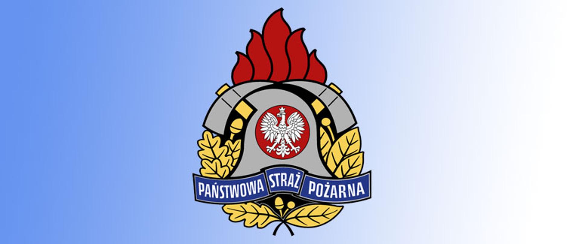 logo Państwowej Straży Pożarnej na którym wodnieje hełm strażacki barwy szarej a w nim, w okręgu barwy czerwonej orzeł w koronie, z tyłu hełmu znajdują się dwa skrzyżowane toporki nad którymi są płomień w postaci pięciu języków ognia, pod hełmem widnieje szarfa z napisem Państwowa Straż Pożarna a pod szarfą są dwa liście, jeden z wieńca laurowego a drugi z dębu, po bokach hełmu z prawej strony trzy liście wieńca laurowego, po lewej stronie dwa liście dębu. Logo na tle koloru niebieskiego przechodzącego w biały.