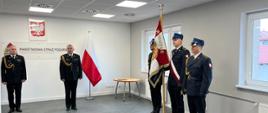 Komendant Powiatowy Państwowej Straży Pożarnej w Człuchowie st. bryg. Radosław Batruch w asyście Zastępcy Komendanta Powiatowego PSP w Człuchowie bryg. Dariusza Dwulit wita funkcjonariuszy i zgromadzonych gości. Po prawej stronie stoi poczet sztandarowy.