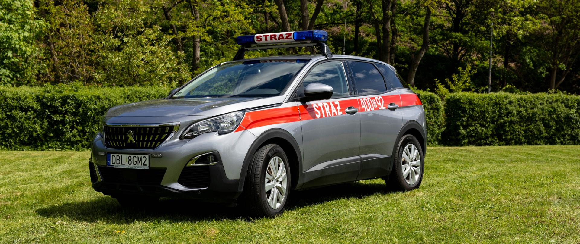 Srebrny, operacyjny SUV marki Peugeot 3008 w wersji strażackiej. Wzdłuż nadwozia ciągnie się czerwony pas z białym napisem „STRAŻ” i numerem operacyjnym „400[D]92”. Na dachu, na czarnych relingach, zamontowana jest niebieska belka sygnalizacyjna z napisem „STRAŻ”. Pojazd stoi na trawie.