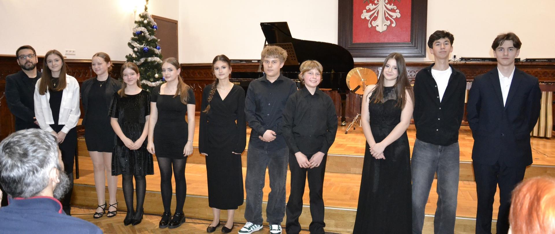 Fotografia przedstawia uczniów klasy II Państwowej Szkoły Muzycznej II stopnia stojących na scenie Sali Królewskiej po koncercie klasowym, który odbył się 28 stycznia 2026 roku.