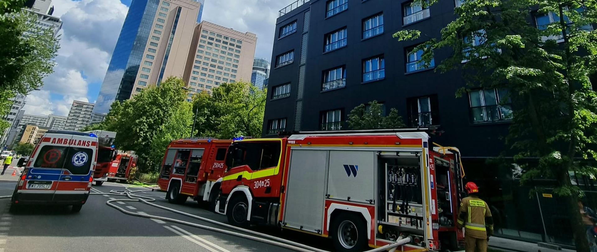 Zdj. 1. Na zdjęciu samochód gaśniczy z JRG 4, karetka. W tle budynek w którym palił się szacht kablowy.
