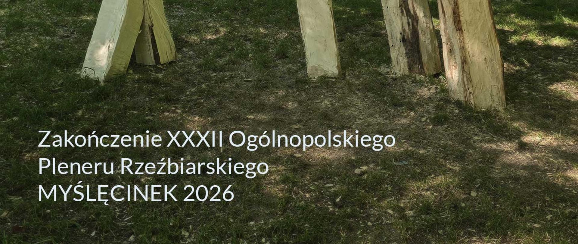 Biały napis na zdjęciu trawy i fragmentu rzeźby w drewnie