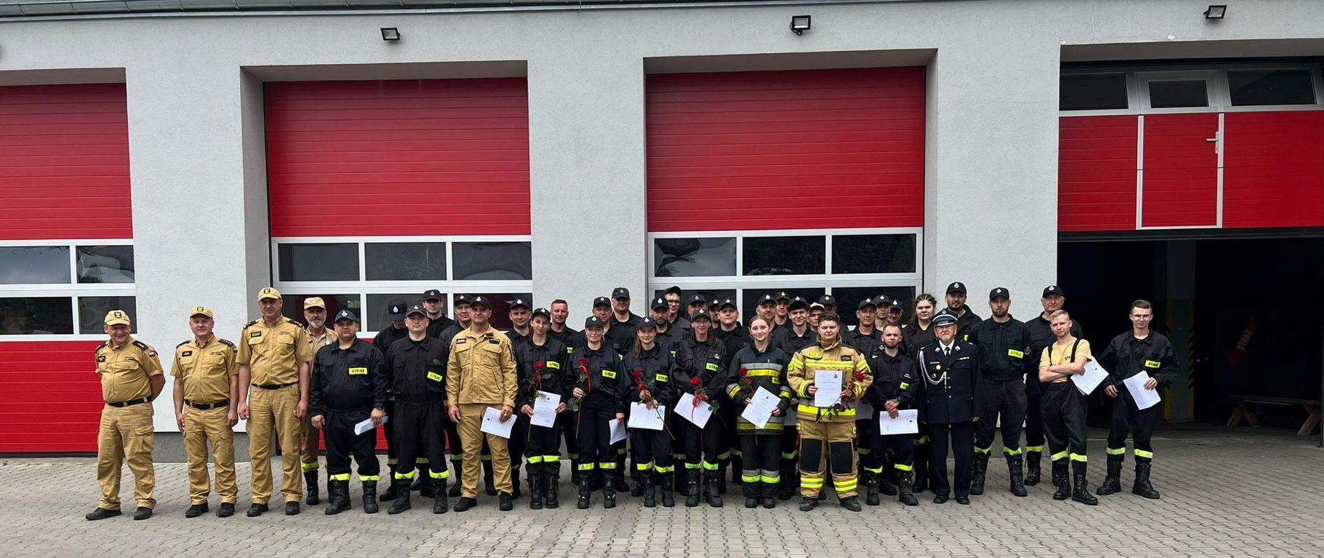 Zdjęcie grupowe strażaków na tle komendy