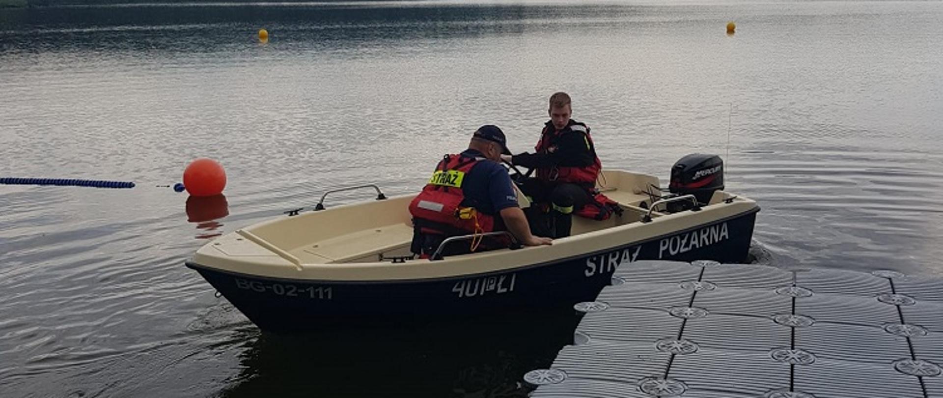 Zdjęcie przedstawia strażaków podczas rozpoznania operacyjnego akwenów wodnych i patrolów z Policją.
W tle jezioro.
