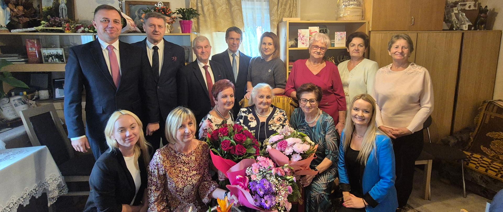 jubilatka z bukietami kwiatów w towarzystwie rodziny