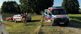 Tragedia nad wodą Zdjęcie przedstawia strażaków podczas działań na tle akwenu 