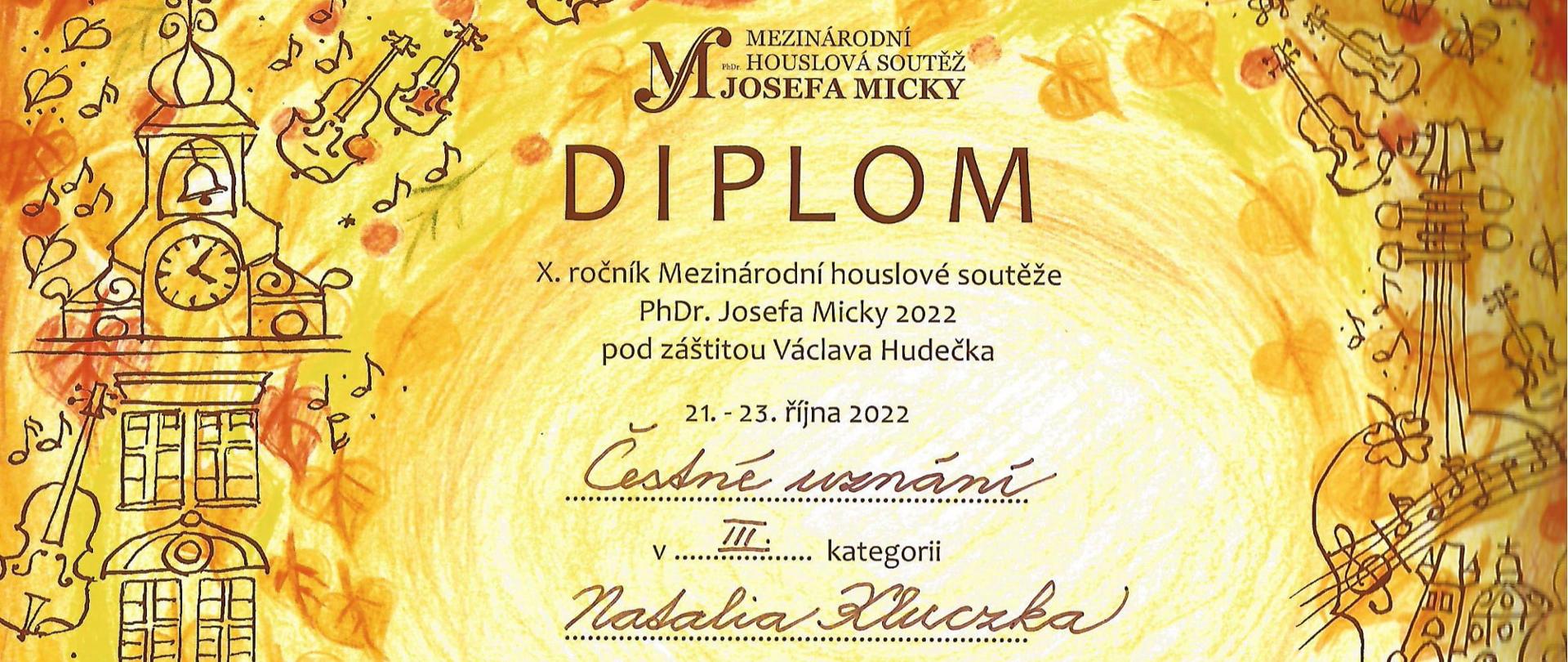 Na pomarańczowym tle widnieją napisy. Dyplom wyróżnienie w III grupie dla Natalii Kluczki. Międzynarodowy Konkurs Skrzypcowy im. Václava Hudečka w Pradze. 21-23. 10. 22 r. Wokół napisów rysunki: po lewej wieża ratuszowa, po prawej skrzypce.