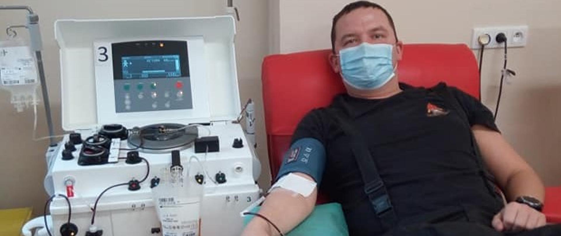 Strażak leży na kozetce i oddaje krew.