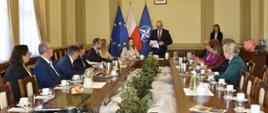 grupa uczestników siedzi przy stole, słucha wypowiedzi mężczyzny, który stoli - wojewody 