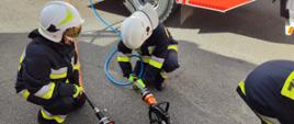 Sprawianie urządzeń hydraulicznych przez strażaków. W tle samochód pożarniczy