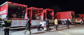Strażacy przygotowują się do rozładowania samochodów strażackich ze sprzętu pożarniczego.