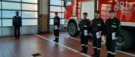 Zdjęcie przedstawia strażaków KP PSP Prudnik, którzy otrzymali listy pochwalne od komendanta. Strażacy stoja w garażu na tle samochodu pożarniczego