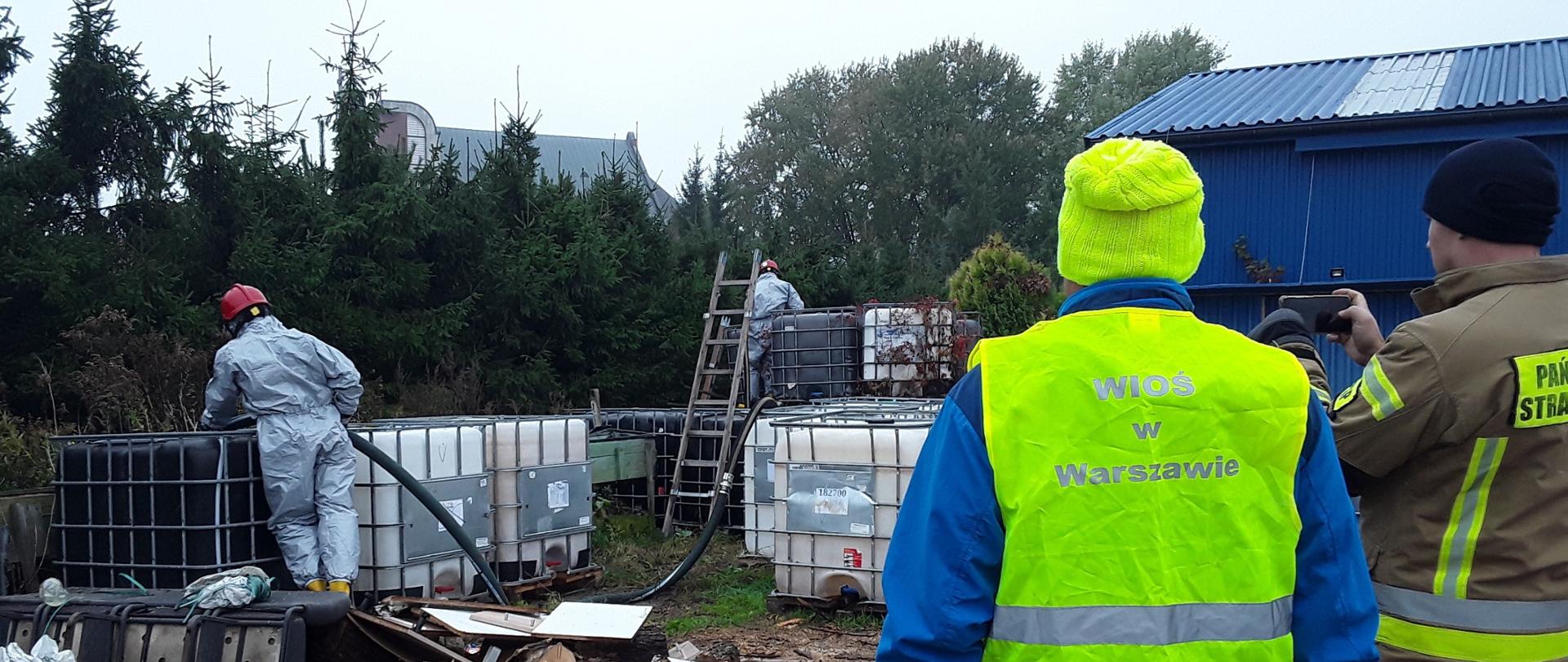 Inspektor Wojewódzkiego Inspektoratu Ochrony Środowiska w Warszawie obserwuje przepompowywanie niebezpiecznej substancji z pojemników o pojemności 1000 l nielegalnie zgromadzonych na otwartym terenie.
